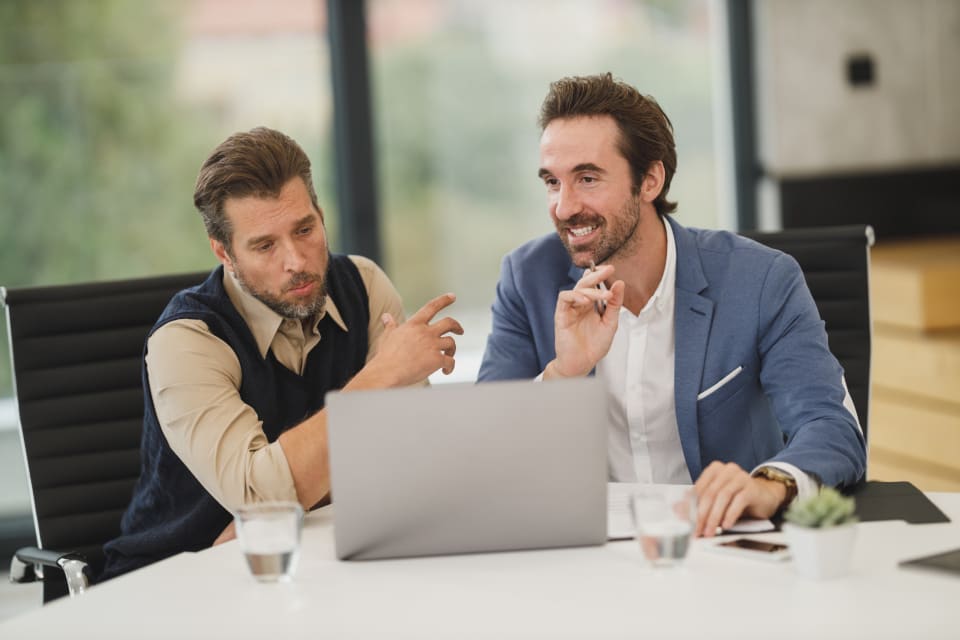 Two colleagues reviewing figures on a laptop