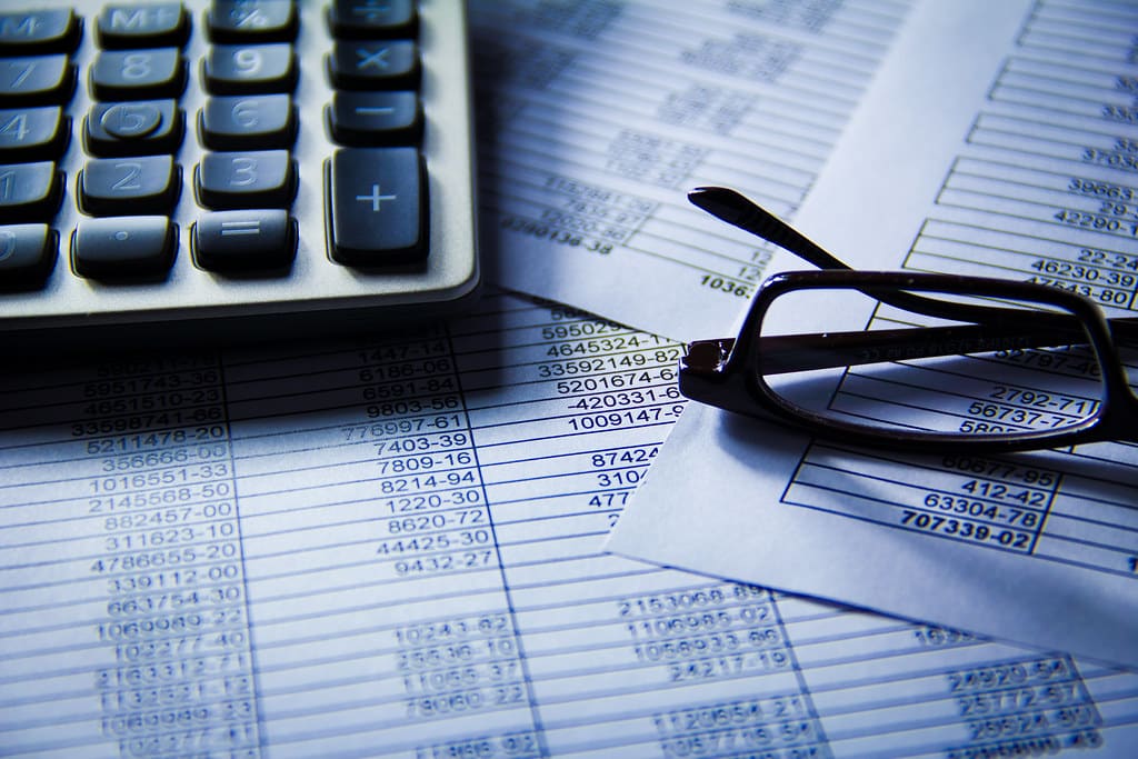 Printed spreadsheet with glasses and a calculator